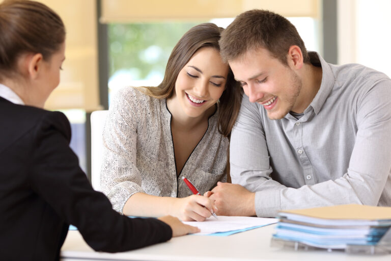 Happy couple signing a contract together at office