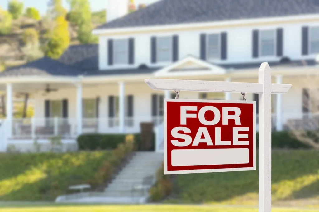 A red for sale sign in front of a white two story home